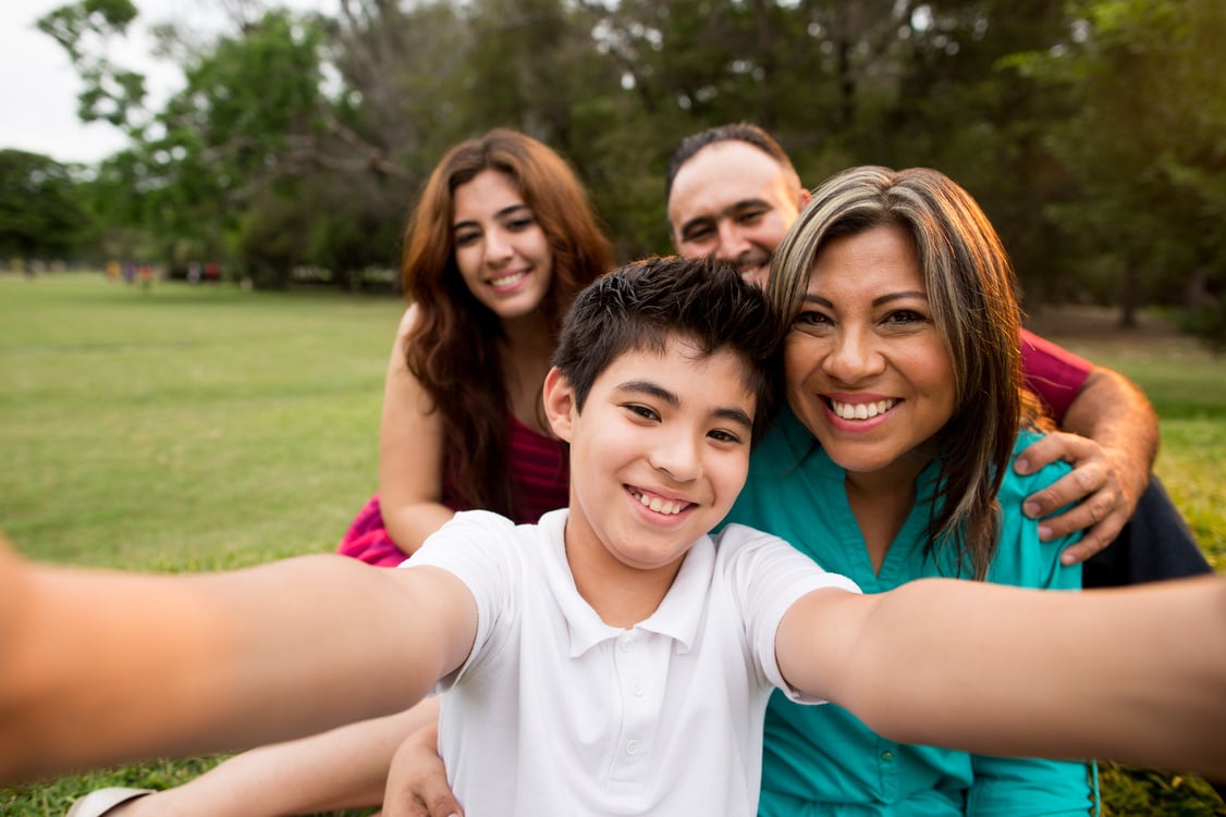 Latin teen son taking selfie picture with family